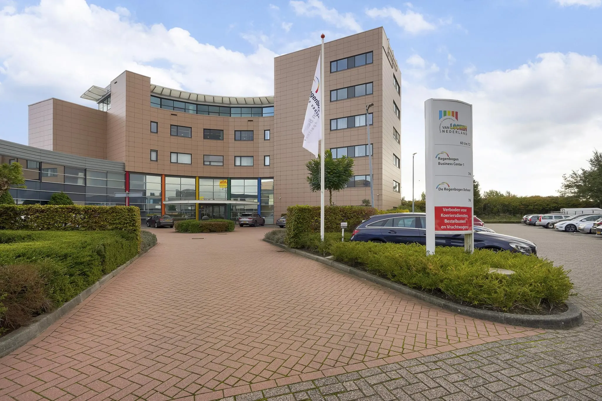 Vooraanzicht van het Regenboog Business Center aan de Laan van s-Gravenmade met parkeerterrein en een informatiebord.